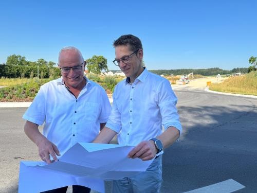 Bürgermeiser Gaus und Georg Mack mit Plan vor dem Baugebiet Hafenäcker III